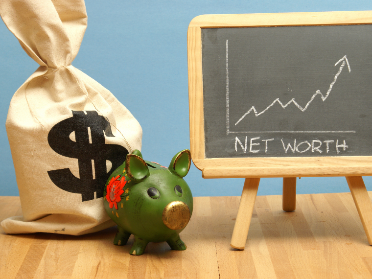 A bag with a dollar sign, a piggy bank, and a chalkboard with a chart drawn in chalk