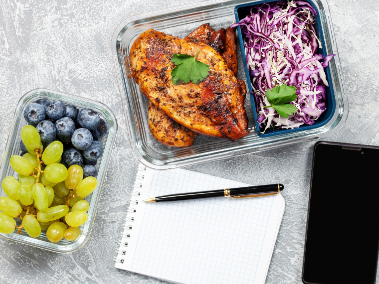 Meal prepped food, a journal and a phone